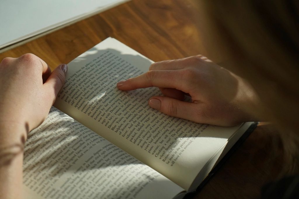 Ръце, които следват с пръст редовете в отворена книга