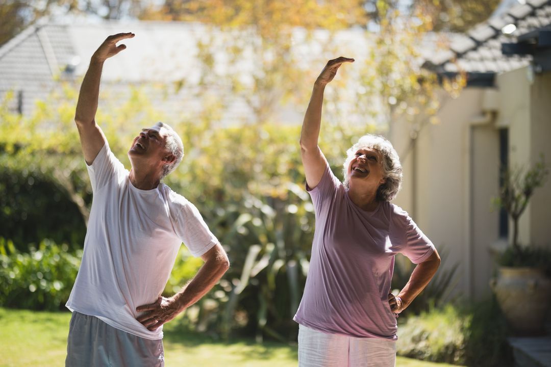 Uśmiechnięta para seniorów przeciąga się razem w słonecznym ogrodzie
