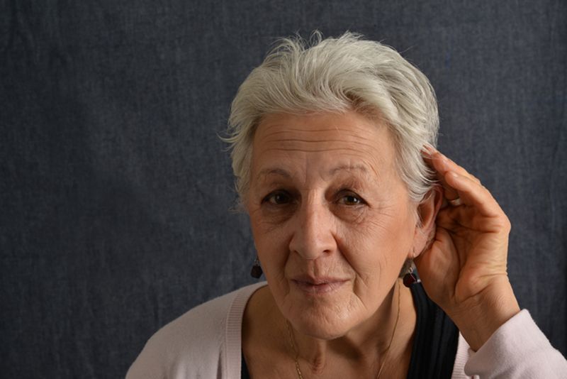 Starija žena prislanja dlan uz uvo i pažljivo pokušava da čuje sagovornika